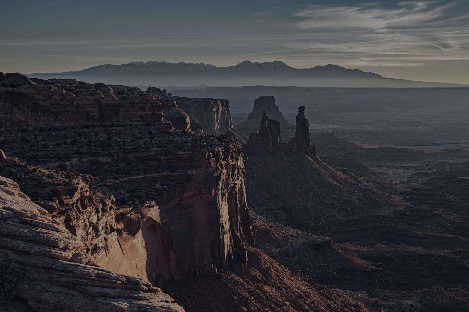 An expansive canyon and distant mountain range at dusk.